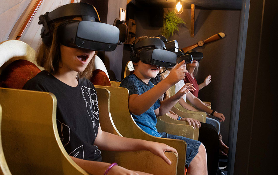 Kinder erleben staunend eine VR-Simulation in alten Theaterstühlen.