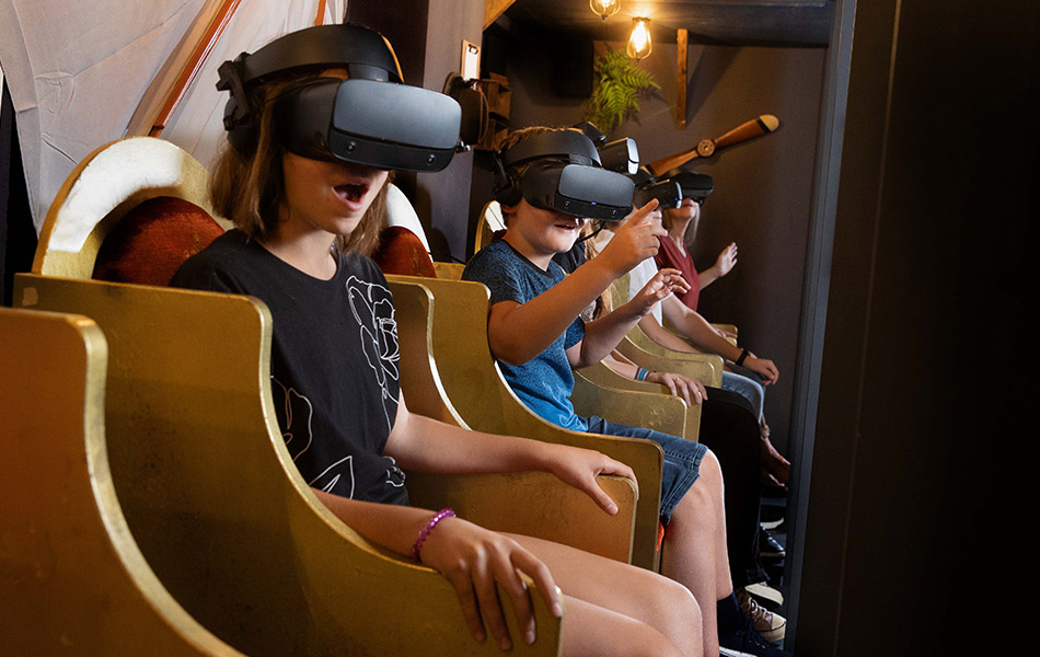 Kinder sitzen mit VR-Brillen in goldenen Sitzen des Senseums und staunen.
